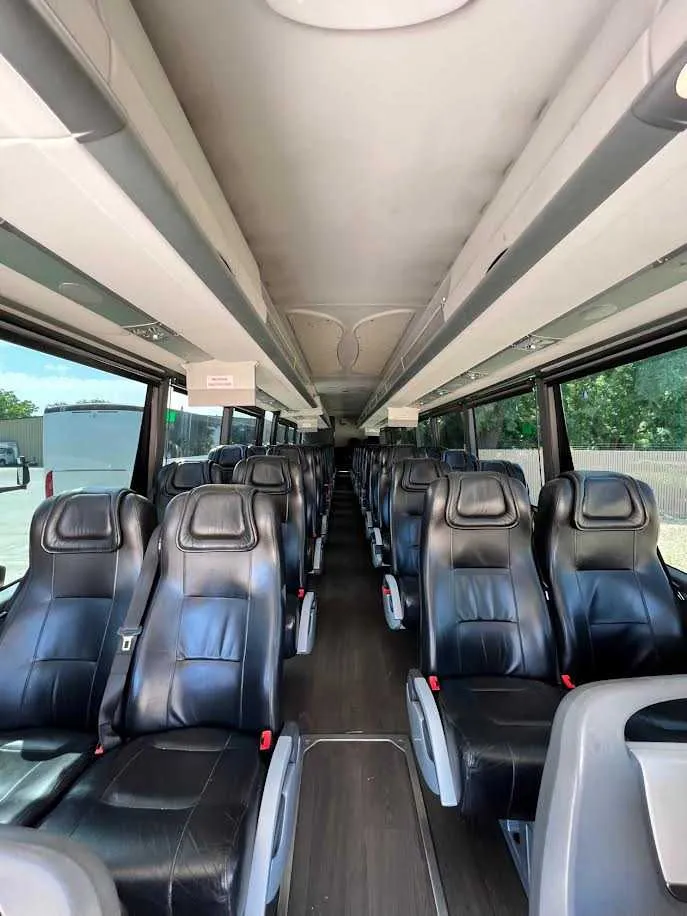 MCI Motorcoach interior with passenger seat belts and overhead parcel racks for charter bus rental