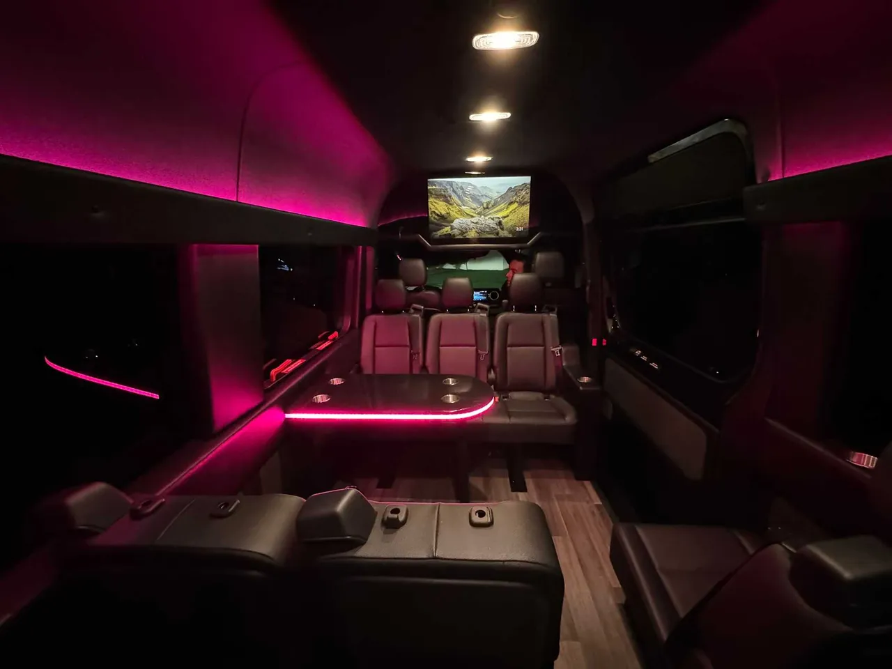 Mercedes Executive Sprinter interior with passenger tables, LED accent lighting and wood-look flooring for party bus rental