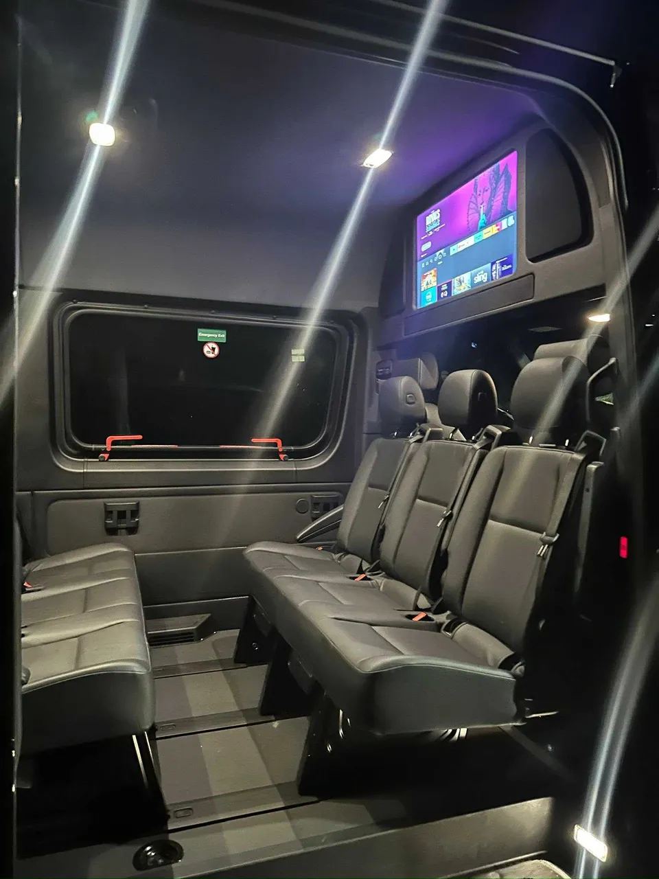 Mercedes Limo Sprinter interior with TV screens and passenger seat belts for party bus rental