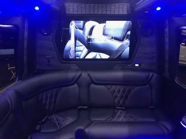 Mercedes Party Bus interior with sofa-style seating, LED accent lighting and TV screens for party bus rental