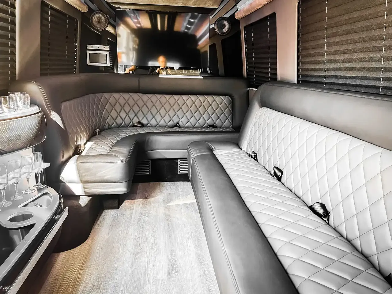Mercedes Sprinter Limo interior with perimeter lounge seating, window shades and wood-look flooring for party bus rental