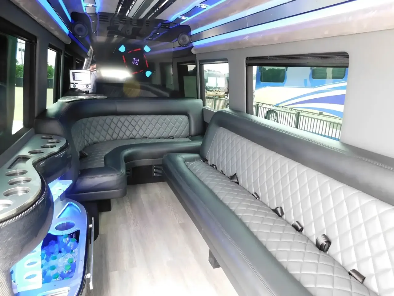 Mercedes Sprinter Limo interior with perimeter lounge seating, LED accent lighting and wood-look flooring for party bus rental