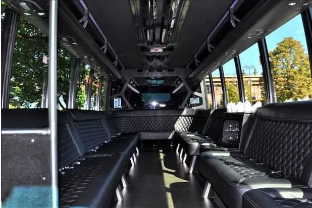 Mini Coach Limo Bus interior with perimeter lounge seating and dance pole for party bus rental