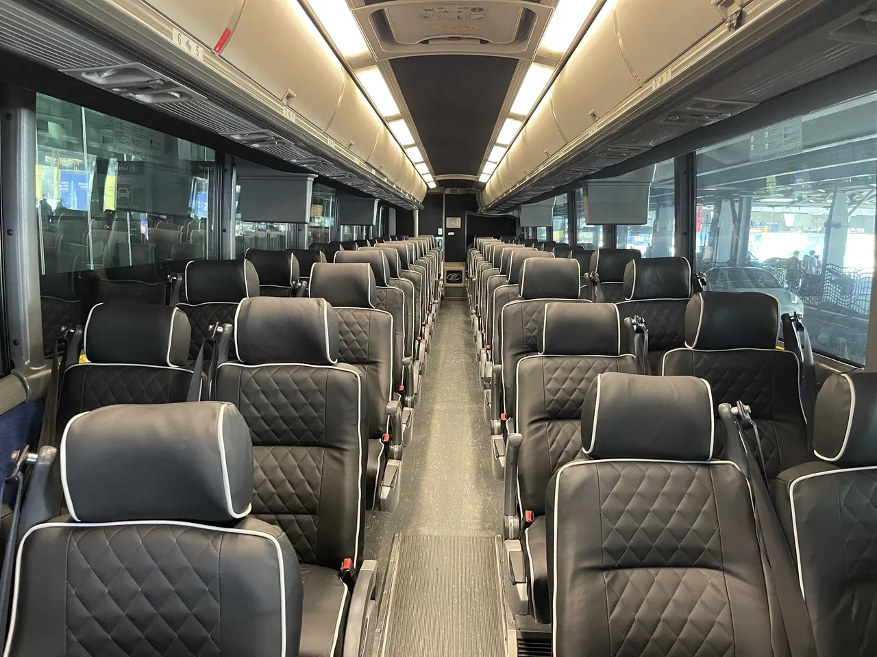 56 Passenger Motorcoach 56 Passenger Motorcoach interior with TV screens and overhead parcel racks for charter bus rental