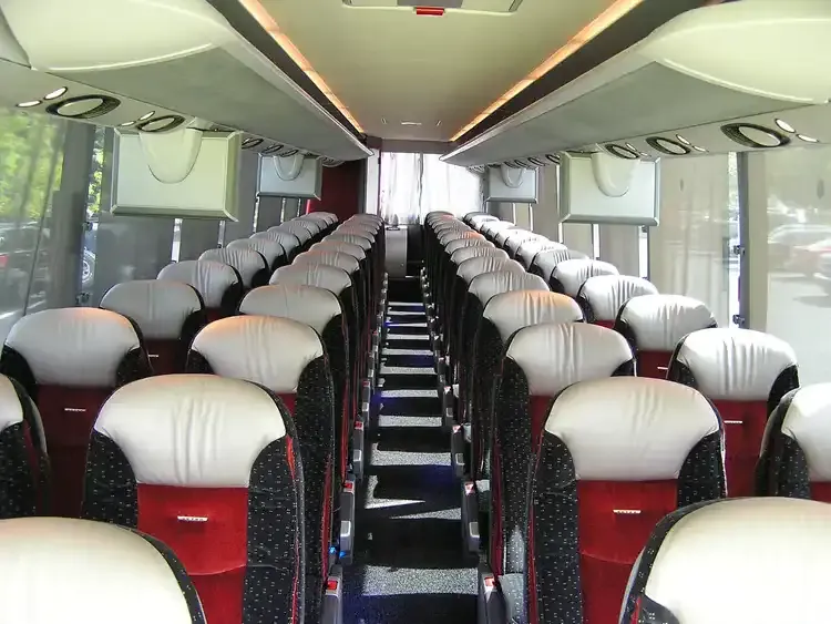 30 Passenger Motorcoach interior with individual air vents and overhead parcel racks for charter bus rental