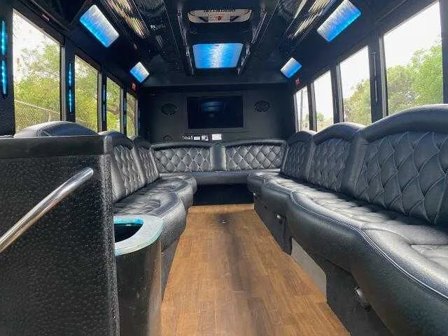 24 Passenger Party Bus interior with perimeter lounge seating, LED accent lighting and LED ceiling lighting for party bus rental
