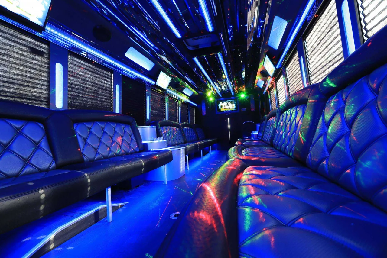 30 Passenger Party Bus interior with perimeter lounge seating, window shades and LED accent lighting for party bus rental