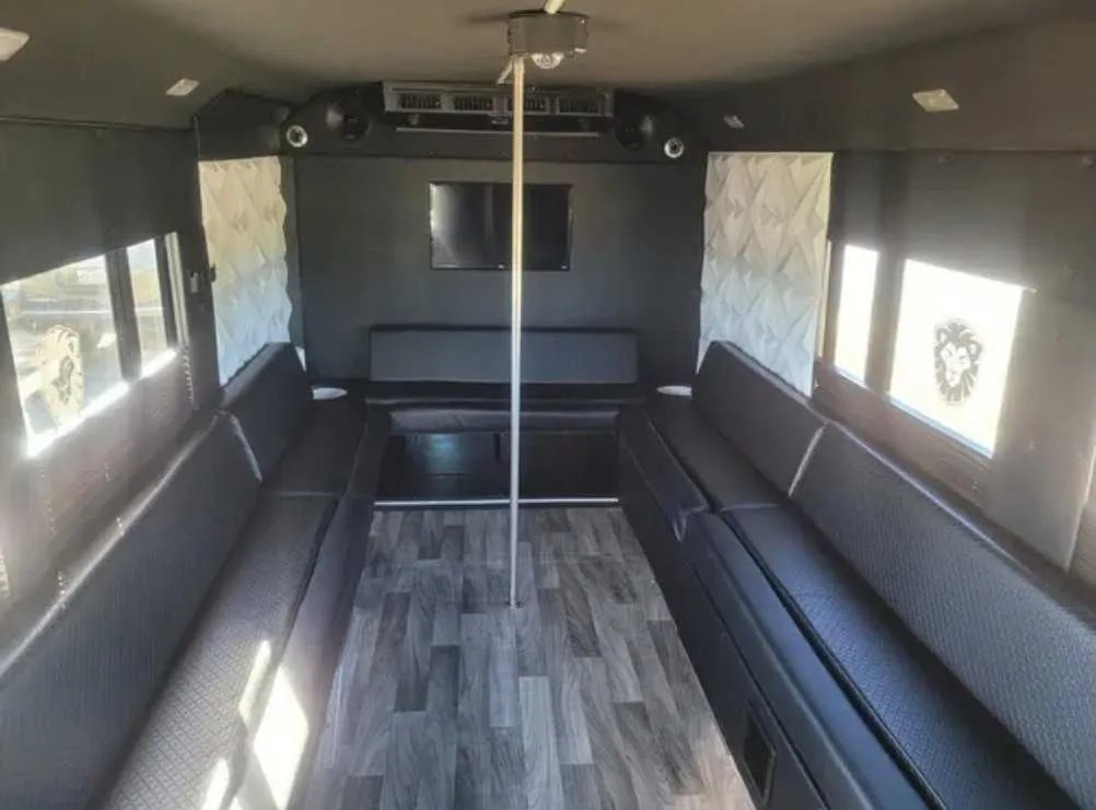 Tuxedo Party Bus interior with perimeter lounge seating, wood-look flooring and TV screens for party bus rental