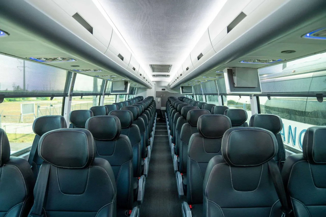 Motorcoach interior with LED ceiling lighting, TV screens and overhead parcel racks for charter bus rental